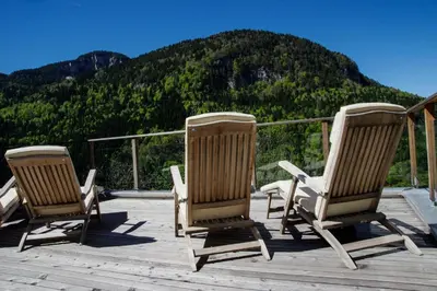 three rocking chairs sitting on a deck with a mountain at Berggasthof Locanda Alpina Dorfner in Montagna