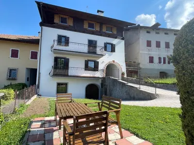 a building with two wooden benches in front of it at Casa Ianes in Ronzone