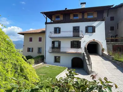 a large white building with a balcony and a courtyard at Casa Ianes in Ronzone
