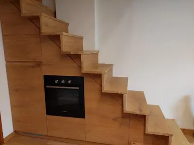 a wooden staircase with an oven in a wooden cabinet at Petit Chalet in Villanova
