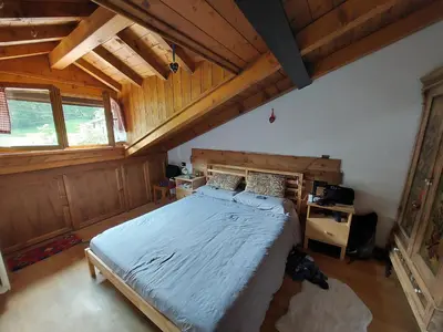 a bedroom with a large bed in a room with wooden walls at Petit Chalet in Villanova