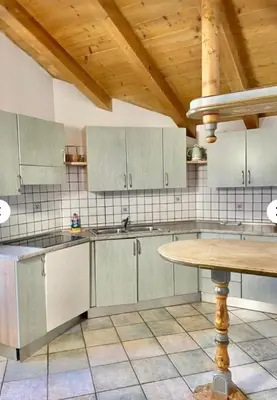 a kitchen with white cabinets and a wooden ceiling at Cèsa Niki in Canazei