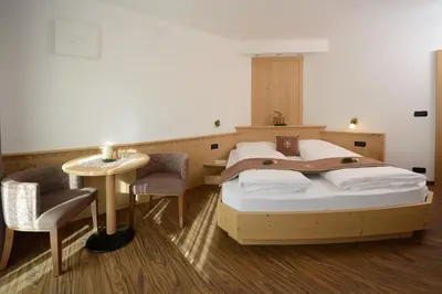 a bedroom with two beds and a table and chairs at Apartments Villa Montana in Ortisei