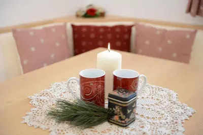 two mugs and a candle on a table at Apartments Villa Montana in Ortisei