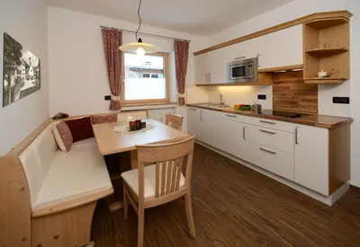 a kitchen with white cabinets and a wooden table at Apartments Villa Montana in Ortisei