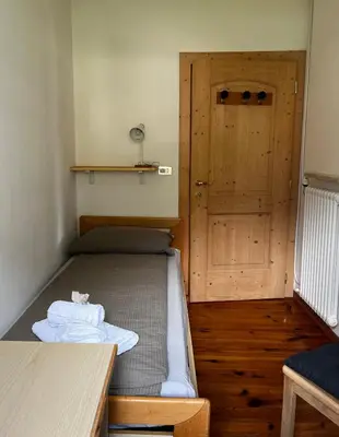 a small room with a bed and a door at Appartamento Le Sipole in Ziano di Fiemme