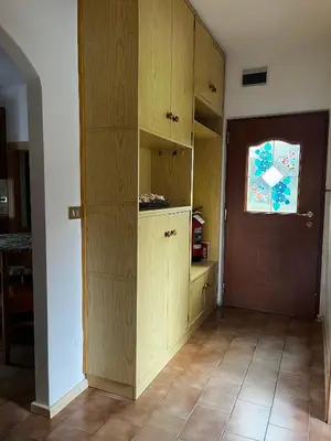a kitchen with wooden cabinets and a door with a window at Appartamento Le Sipole in Ziano di Fiemme