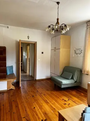 a living room with a green couch and wooden floors at Appartamento Le Sipole in Ziano di Fiemme