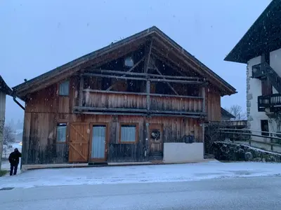 a man standing in front of a wooden building at Chalet le Dolomiti in Borca di Cadore