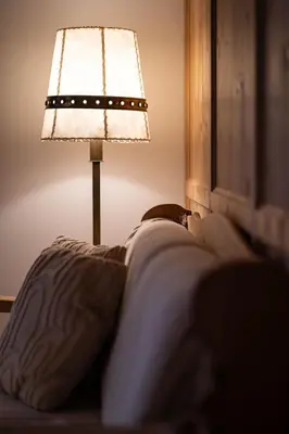 a lamp sitting on a bed next to a pillow at Traditional Cozy Apartment in Tirolo