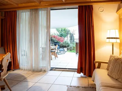 a living room with a sliding glass door leading to a patio at Traditional Cozy Apartment in Tirolo