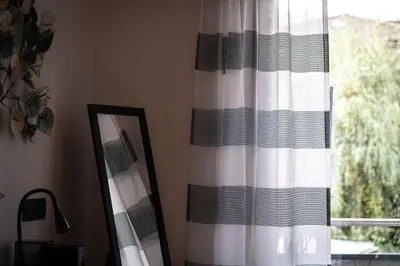 a mirror and a curtain next to a window at Laubennest 3 in Merano