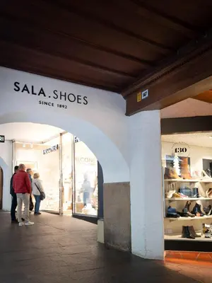 a store with people standing outside of a shoe store at Laubennest 3 in Merano