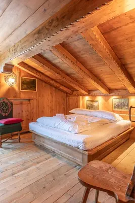a large bed in a room with wooden ceilings at Casa Cirmoli, confortevole mansarda con balcone panoramico in Cortina dʼAmpezzo