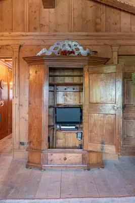a entertainment center with a tv in a wooden wall at Casa Cirmoli, confortevole mansarda con balcone panoramico in Cortina dʼAmpezzo