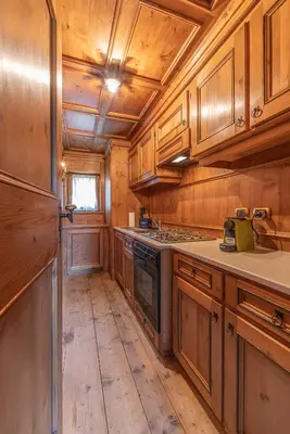 a kitchen with wooden cabinets and a stove at Casa Cirmoli, confortevole mansarda con balcone panoramico in Cortina dʼAmpezzo