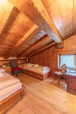 a large room with two beds and a window at Casa Cirmoli, confortevole mansarda con balcone panoramico in Cortina dʼAmpezzo
