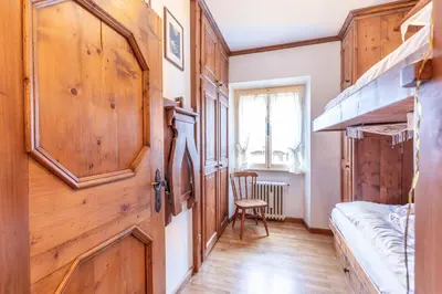 a room with a wooden door and a chair in it at Casa via dei Prati, ampia e confortevole in centro in Cortina dʼAmpezzo