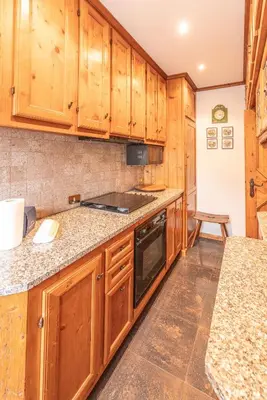 a kitchen with wooden cabinets and granite counter tops at Casa via dei Prati, ampia e confortevole in centro in Cortina dʼAmpezzo