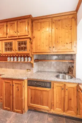 a kitchen with wooden cabinets and a sink at Casa via dei Prati, ampia e confortevole in centro in Cortina dʼAmpezzo