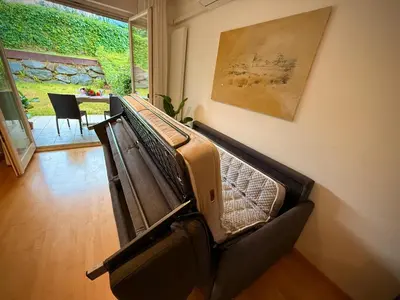 a empty bed in a living room with a table at MarlingoStar con giardino e garage in Marlengo