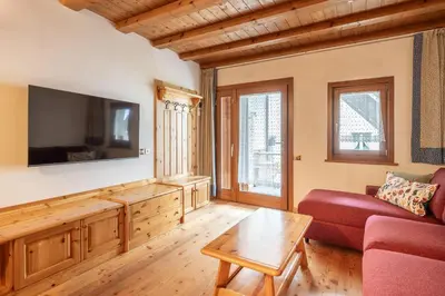 a living room with a red couch and a tv at Beautiful ground floor flat few steps from centre in Cortina dʼAmpezzo