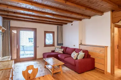 a living room with a red couch and a table at Beautiful ground floor flat few steps from centre in Cortina dʼAmpezzo