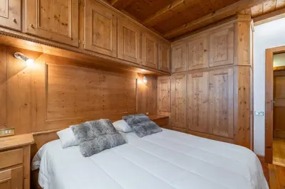 a bedroom with a white bed with wooden cabinets at Beautiful ground floor flat few steps from centre in Cortina dʼAmpezzo
