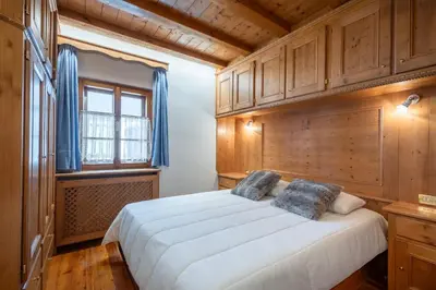 a bedroom with a large white bed with wooden cabinets at Beautiful ground floor flat few steps from centre in Cortina dʼAmpezzo