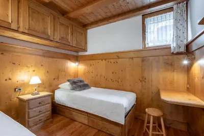 a bedroom with a bed and a desk and a stool at Beautiful ground floor flat few steps from centre in Cortina dʼAmpezzo