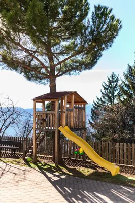 a playground with a yellow slide next to a tree at Hotel Restaurant Alber in Verano