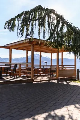 a wooden gazebo with benches and tables at Hotel Restaurant Alber in Verano