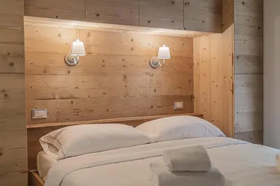 a bedroom with a large bed in a room with wooden walls at Alpine Heart in Falcade