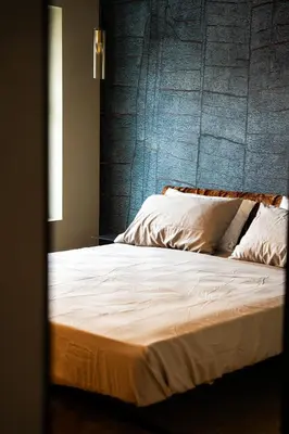 a bed with white sheets and a blue wall at KODERLE SUITE K4 Zampa D Orso in Brunico