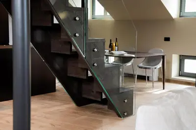 a glass staircase in a room with a table and chairs at KODERLE SUITE K5 Stella Alpina in Brunico
