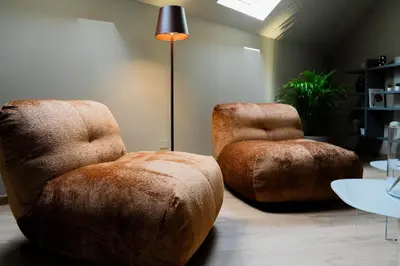 two ottoman chairs and a lamp in a room at KODERLE SUITE K5 Stella Alpina in Brunico