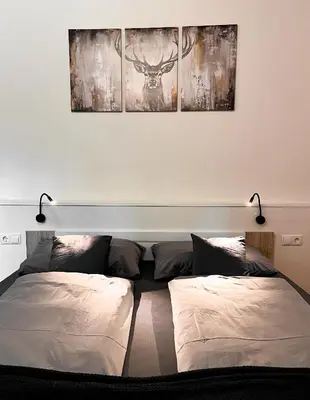 two beds in a room with two paintings on the wall at Studio Cervus with BrixenCard in Bressanone