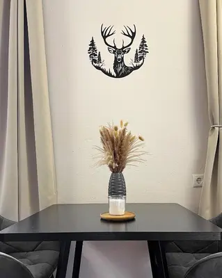 a black table with a deer head and trees on a wall at Studio Cervus with BrixenCard in Bressanone