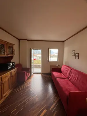 a living room with a red couch and a table at Gianni's Home2 Santa Cristina VG in Santa Cristina in Val Gardena