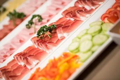 a display of meat and cucumbers on plates in a store at Hotel Pütia in Antermoia