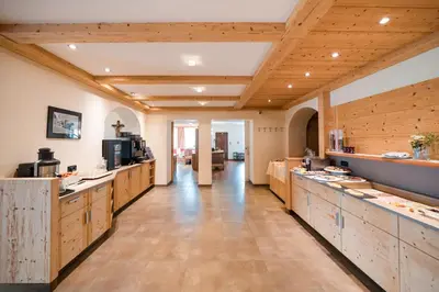 a large kitchen with wooden cabinets and a long hallway at Hotel Pütia in Antermoia