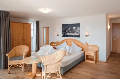 a bedroom with a bed and a table and chairs at Hotel Pütia in Antermoia
