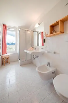 a white bathroom with a sink and a toilet at Hotel Pütia in Antermoia