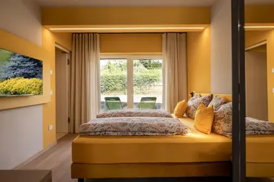 a bedroom with yellow walls and a large window at Villa Sawian in Appiano sulla Strada del Vino