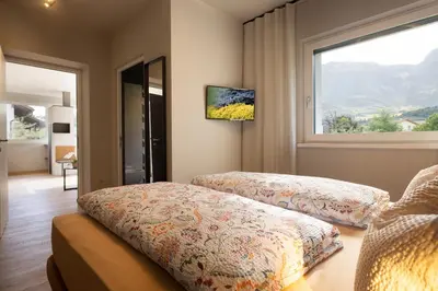 a bedroom with two beds and a large window at Villa Sawian in Appiano sulla Strada del Vino
