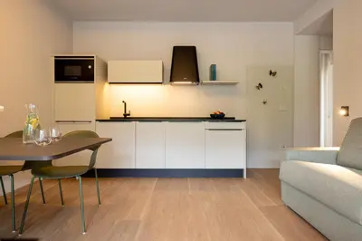a kitchen with white cabinets and a table and a couch at Villa Sawian in Appiano sulla Strada del Vino