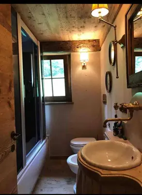 a bathroom with a sink and a toilet and a window at Cottage Cortina d Ampezzo in Cortina dʼAmpezzo