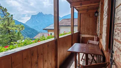 a wooden balcony with a table and a view of mountains at Tabia del Caser in San Tomaso