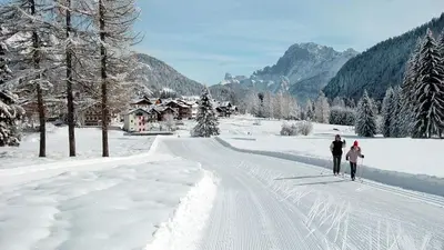 two people cross country skiing down a snow covered road at Tabia del Caser in San Tomaso