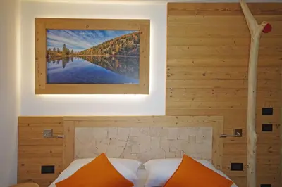 a bed with orange pillows and a picture on the wall at Hotel Aurai in Osteria Alpina